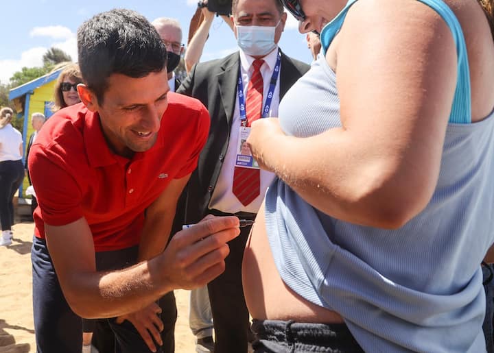 Novak Djokovic smiles on as he gives an autograph to a fan on his bare body. The Serbian has always been a jolly tennis player throughout his career.  (Image Credits- AP/PTI)
