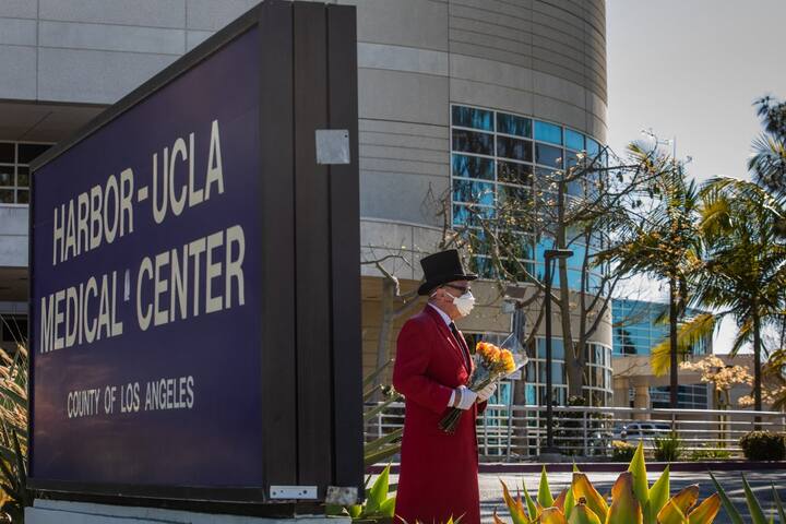 Fan Gregg Donovan, holding flowers, stands in front of the main entrance of the Harbor UCLA Medical Center in Torrance, California on February 23, 2021, where the US Golf star Tiger Woods is hospitalized after a roll-over car crash in Palos Verdes. PIC/AFP