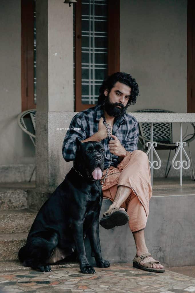 கருப்பு நாயை பிடித்துக் கொண்டு முறைக்கும் டோவினோ