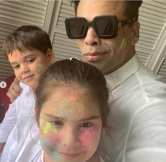 Yash & Roohi Johar- Filmmaker Karan Johar shared this adorable pic posing with his twins as the trio wear matching white outfits for Holi.[pic credit: Instagram/Karan Johar]