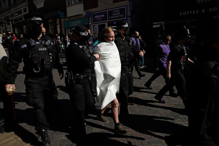 A topless protester who shouted save the planet, is taken away by police officers after they put a cover over her body outside Windsor Castle during the funeral of Britains Prince Philip in Windsor. (Image: PTI)