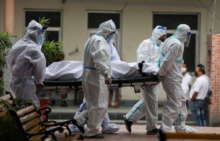 Health workers and family members carry the body of a patient who died of Covid in Jammu. As cases continue to rise, several cities have been brought under weekend lockdowns, night curfews or lockdown-like restrictions. (Image: PTI)