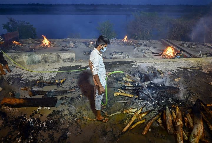 A worker douses the fire of Covid victims at Bhairav Ghat Hindu Crematory as covid cases surge in Kanpur. This is the second straight day that the country is reporting over three lakh cases. (Image: PTI) 