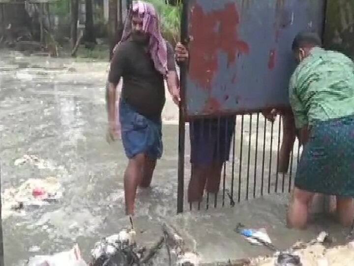 மழையால் வெள்ளம் சூழ்ந்துள்ள நிலையில் இரும்புவாயிலை சரிசெய்யும் நபர்கள்