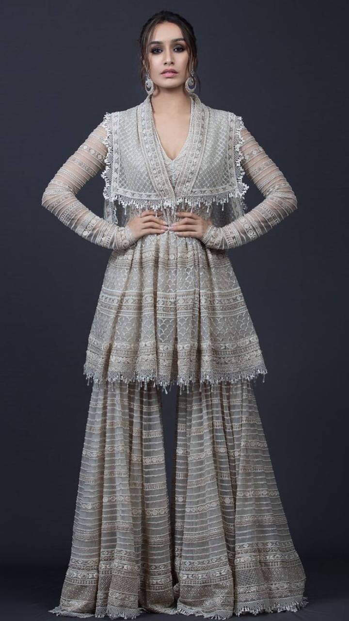 इस आइवरी-ग्रे मल्टी-टियर शरारा में श्रद्धा कपूर हमेशा की तरह खूबसूरत नज़र आ रही हैं. हैवी शरारा सूट को एक्ट्रेस ने स्टेटमेंट ईयररिंग्स, सिल्वर बिंदी और नो मेकअप के साथ पेयर करके लुक को पूरा किया.