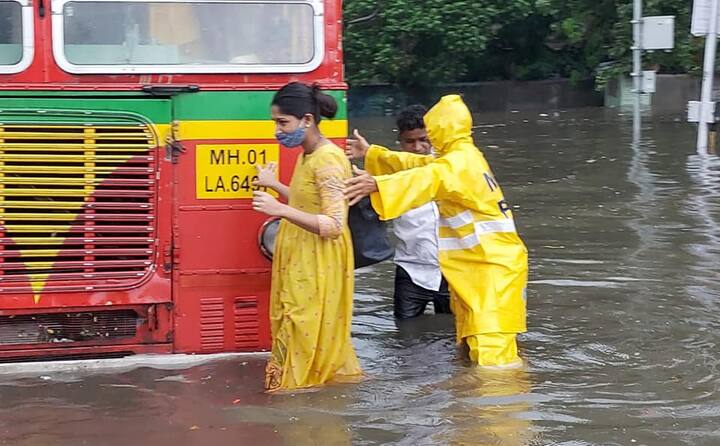 பேருந்தில் இருந்து இறங்கி மழைநீரில் நடந்து செல்லும் பெண்மணி
