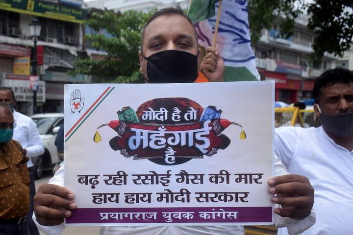 Prayagraj: A Congress party worker holds a placard during a protest against frequent hikes in the prices of petrol and diesel, outside a fuel station in Prayagraj. (Image: PTI)