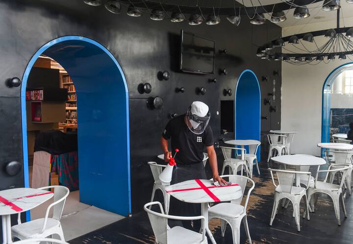 Ahead of the complete unlock, workers clean table and sanitize restaurants in Connaught Place ahead of its reopening, as part of governments order of gradual unlocking of COVID-induced restrictions. (Image: PTI)