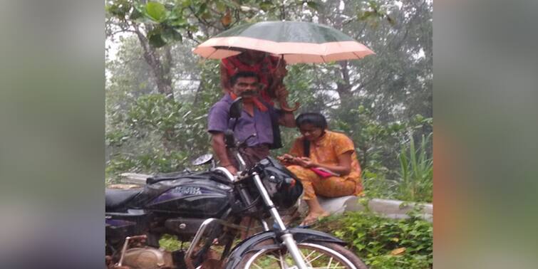 Viral photo: Karnataka man holds umbrella over his daughter as she attends online class during rain by the road Father's Day : রাস্তায় বৃষ্টি মাথায় অনলাইন ক্লাসে মগ্ন যুবতী! মাথায় ছাতা ধরে বাবা; ভাইরাল ছবি