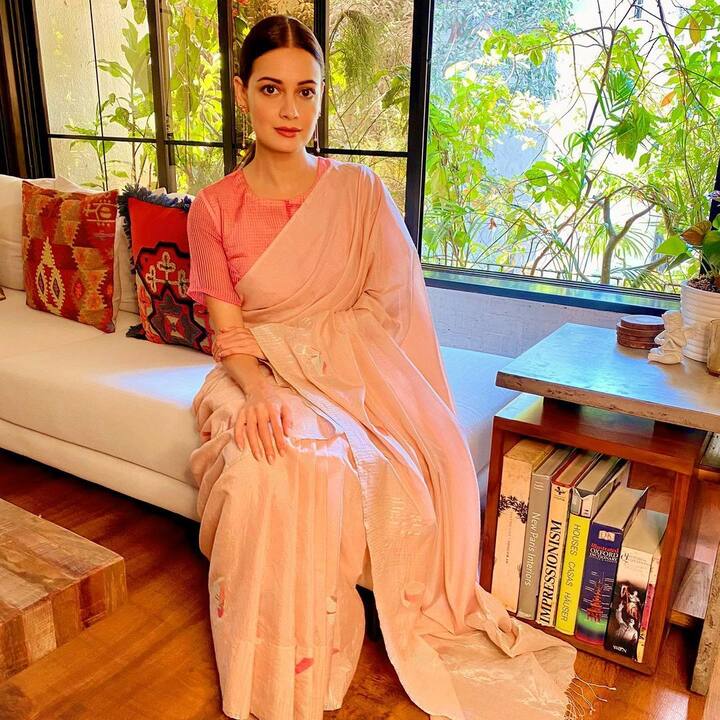 खिड़की के पास बैठने के लिए एक व्हाइट सोफा लगाया गया है जिसपर मल्टीकलर के कुशन रखे हैं