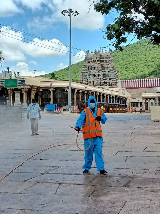 அழகர்கோயில் வளாகத்தில் கிருமி நாசினி தெளிக்கும் ஊழியர்