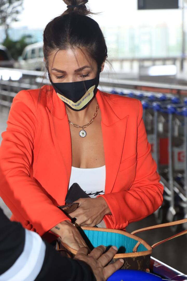 Malaika can be seen wearing a white crop top and a ripped jeans to complete her entire look. She styled her hair into a messy bun and wore mask for protection. (Image courtesy – Manav Manglani)