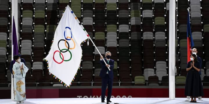 President of the International Olympic Committee (IOC) Thomas Bach waves the Olympic flag between Tokyo's governor Yuriko Koike (L) and Paris Mayor Anne Hidalgo (R). (Image: AFP)