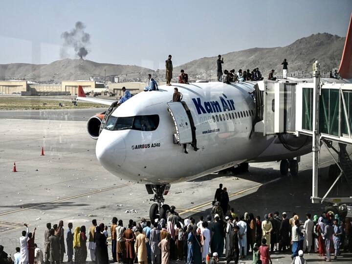 Afghan people climb atop a plane as they wait at the Kabul airport in Kabul on August 16, 2021. (Wakil Kohsar / AFP)