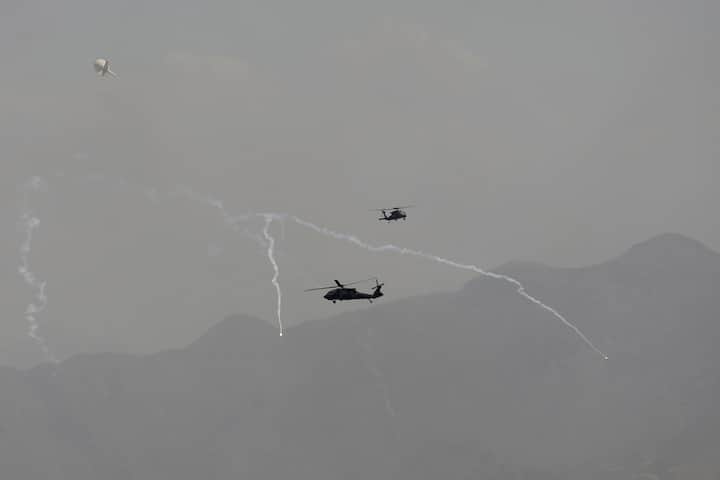 Anti-missile decoy flares are deployed as U.S. Black Hawk military helicopters and a dirigible balloon fly over the city of Kabul, Afghanistan, Sunday, Aug. 15, 2021. Taliban fighters entered the outskirts of the Afghan capital on Sunday and said they were awaiting a “peaceful transfer” of the city after promising not to take it by force, but amid the uncertainty panicked workers fled government offices and helicopters landed at the U.S. Embassy. (Image Source: AP/Rahmat Gul)