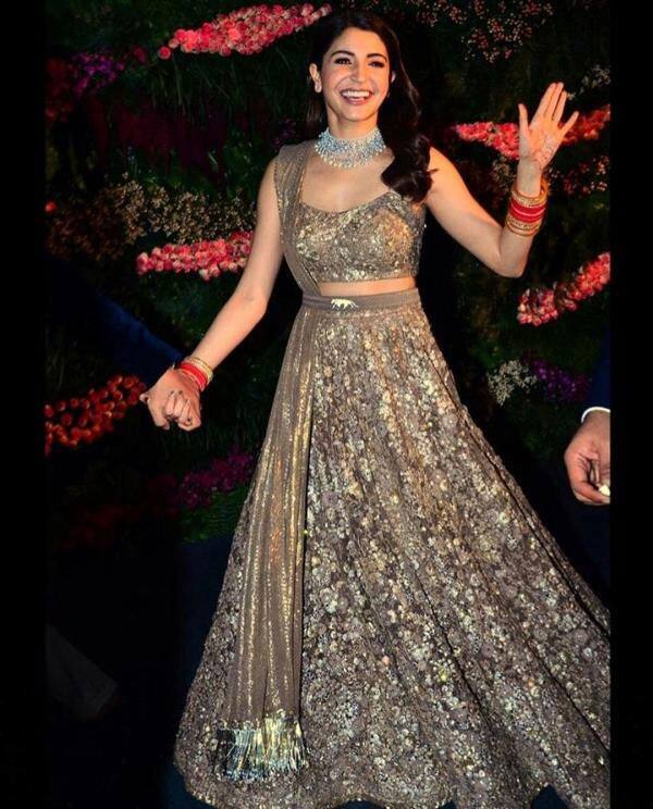 गोल्डन कलर हैवी एम्ब्रोइडरी लहंगा जिसकी चुन्नी को बेल्ट से अटैच करते हुए अनुष्का ने अपने रिसेप्शन में पहना था. ये डिजाइनगर और काफी महंगा लहंगा था. (फोटो – सोशल मीडिया)
