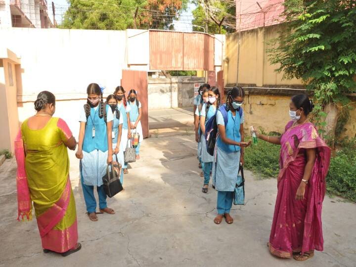 கிருமிநாசினி எடுத்துக்கொண்டு பள்ளி மாணவிகள் வகுப்பறைக்கு செல்லும் காட்சி.