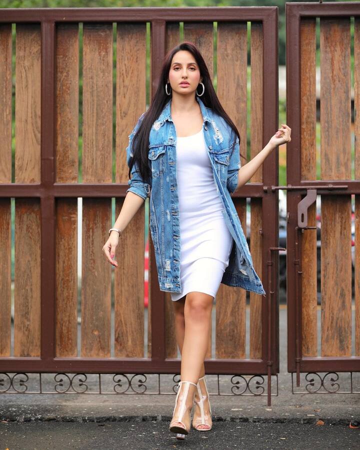 Denim essentials- स्ट्रीट स्टाइल की लिस्ट बिना डेनिम का ज़िक्र किए अधूरी है. यहां नोरा अपनी सिग्नेचर व्हाइट बॉडीकॉन ड्रेस के ऊपर एक लम्बी डेनिम जैकेट पहने दिखीं. सिल्वर हूप इयररिंग्स और मिनिमल, नेचुरल-टोन्ड मेकअप ने उनके लुक को कम्पलीट किया था.