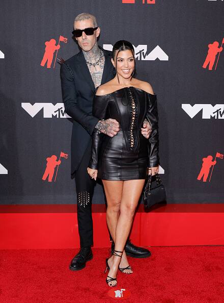 The 42-year-old reality star, Kourtney Kardashian walked the red carpet in a leather off-the-shoulder minidress with lace-up detailing while her 45-year-old musician beau chose a suit with spikes on the shoulders — and no shirt underneath. [gettyimages]