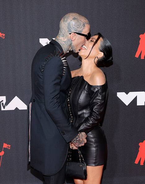 As they posed for photos in matching black ensembles, Kardashian and Barker held hands and shared a passionate lip-lock. [gettyimages]
