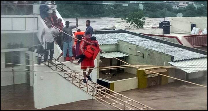 हालात बेकाबू होता देख प्रशासन न मदद मुहैया कराने के लिए एनडीएरएफ की टीमों को लगाया है. एक एनडीआरएफ का जवान भारी बारिश के बाद बाढ़ के हालात के बीच एक बच्चे को रेस्क्यू करता नज़र आया. ये तस्वीर जामनगर की है. (तस्वीर: पीटीआई)