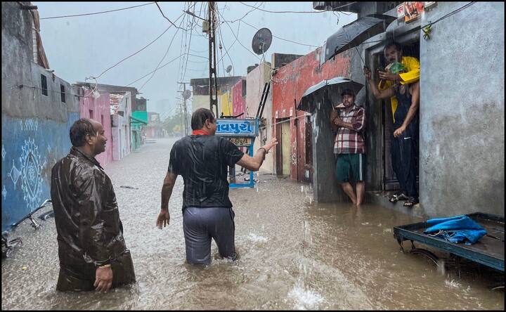 राजकोट में बीजेपी कार्यकर्ता स्थानीय लोगों से इलाके को खाली करने की बात कहते नज़र आए. दरअसल राजकोट में अभी और बारिश हो सकती है, जिससे हालात बिगड़ने का अंदेशा है.  (तस्वीर: पीटीआई)