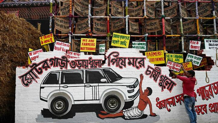 ਉਸ ਦੇ ਆਲੇ-ਦੁਆਲੇ ਇੱਕ ਕਾਰ ਦਾ ਸਕੈਚ ਹੈ ਤੇ ਉਸ ਦੇ ਰਸਤੇ 'ਚ ਕਿਸਾਨ ਪਿਆ ਹੈ। ਇਸ ਦੇ ਹੇਠਾਂ ਬੰਗਾਲੀ ਵਿੱਚ ਲਿਖਿਆ ਹੈ: ਮੋਟਰ ਵਾਹਨ ਉੱਡੇ ਧੂਲੋ ਨਿੱਚੇ ਪੋਰ ਚਸੀਗੁਲੋ ਯਾਨੀ ਕਾਰ ਧੂੰਆ ਉਡਾਉਂਦੀ ਹੋਈ ਜਾ ਰਹੀ ਹੈ ਤੇ ਕਿਸਾਨ ਉਸ ਦੇ ਪਹੀਏ ਹੇਠ ਆ ਰਹੇ ਹਨ।