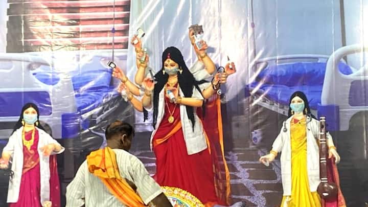 দেবীর পরণে বেনারসী বা ভারি সাজ নেই, প্রত্যেকেই সাধারণ তাঁতের শাড়ি পরেছেন। আর তার উপর রয়েছে চিকিৎসকদের পোশাক।
