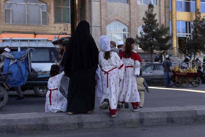 குழந்தைகளோடு சாலையைக் கடக்கும் ஆப்கானிய பெண் (Courtesy:Reuters)