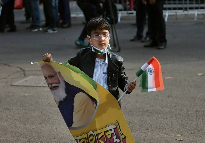 A child holds the national flag and a poster of Prime Minister Narendra Modi to welcome him in Italy. (Image Source: PTI)