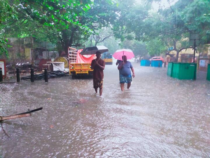 முட்டியளவிற்கு தண்ணீரில் குடைபிடித்து நடந்து செல்லும் பொதுமக்கள்