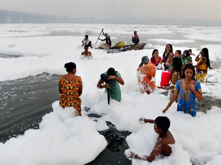 Devotees offer prayers as part of the rituals of four days long Chhath Puja celebrations, as toxic foam floats on the surface of polluted Yamuna river at Kalindi Kunj, in New Delhi, Monday, Nov. 8, 2021. (PTI Photo/Kamal Kishore)
