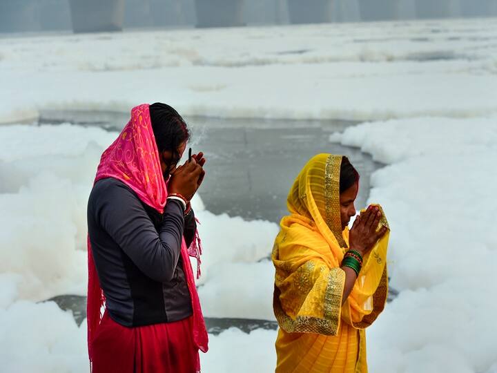Devotees takes a bath as part of the rituals of four days long Chhath Puja celebrations, as toxic foam floats on the surface of polluted Yamuna river at Kalindi Kunj, in New Delhi, Monday, Nov. 8, 2021. (PTI Photo/Kamal Kishore)