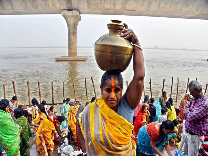 A devotee carries a vessel after offering prayers at the banks of River Ganga during the first day of four days long Chhath Puja celebration, in Patna, Monday, Nov. 8, 2021. (PTI Photo)