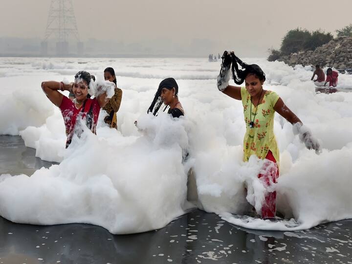 Women devotees take bath as part of the rituals of four days long Chhath Puja celebrations, as toxic foam floats on the surface of polluted Yamuna river at Kalindi Kunj in New Delhi, Monday, Nov. 8, 2021. (PTI Photo/Kamal Kishore)