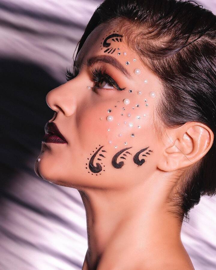 Rubina opted for a dramatic make-up. She got the left side of her face painted with black patterns, decorated with pearls and white stones. Her hair was tied in a side bun. (Image Courtesy: @rubinadilaik/Instagram)