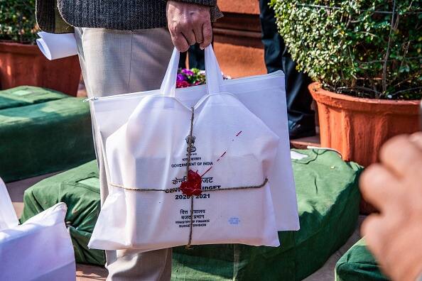Workers carrying sealed bags containing copies of the union budget 2020-21 under the watch of security personnel, inside the Parliament complex, on February 1, 2020. (Getty Image)