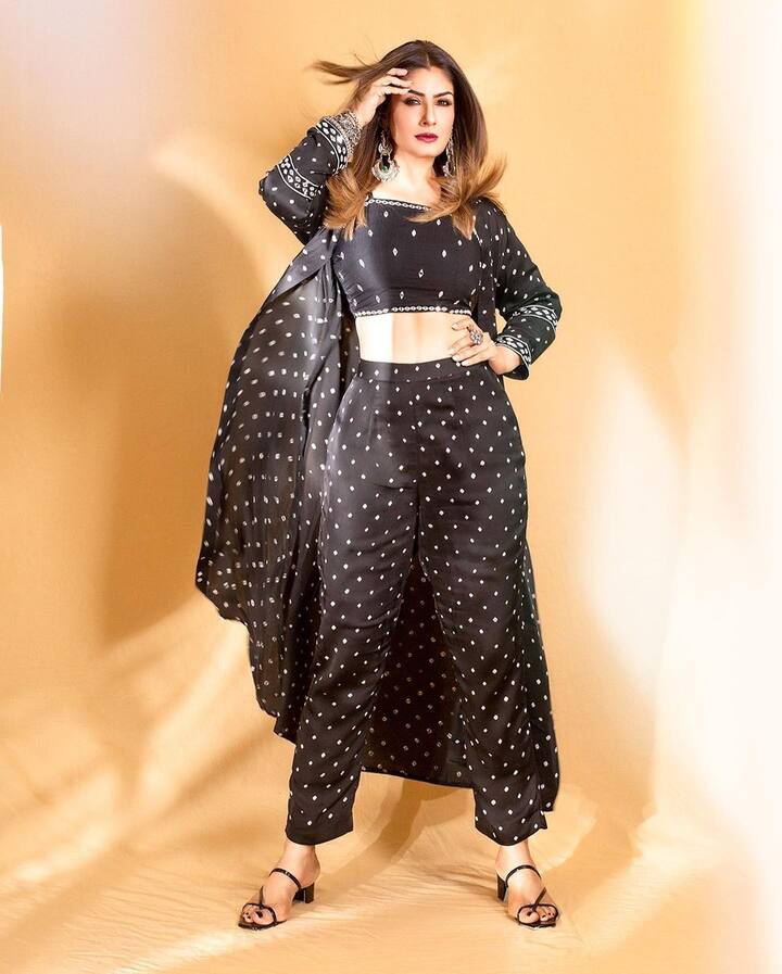 She looks elegant in an Indo-Western outfit by JhanviAakrati and Sonya Shaikh. She is wearing plain black striped sandals with the dress. (Image: Instagram/officialraveenatandon)