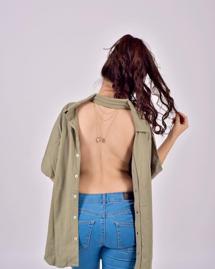 उर्फी ने बैक ओपन उल्टी शर्ट पहनी है. ओलिव कलर की इस शर्ट को समझना थोड़ा मुश्किल है. उर्फी ने इस शर्ट को आगे से पीछे की तरफ पहना है. जिसे बैक से ओपन रखा है. उसके साथ ही शर्ट का कॉलर आगे की तरफ है. उन्होंने इसके साथ ही गले में चेन पहनी है. उसे भी उल्टा करके पहना है. (फोटो-सोशल