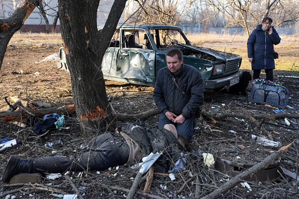 A man mourns near a body as airstrike damages an apartment complex outside of Kharkiv, Ukraine on February 24, 2022. (Getty Images)