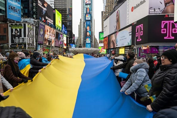 People holding a large Ukrainian flag gather for a 