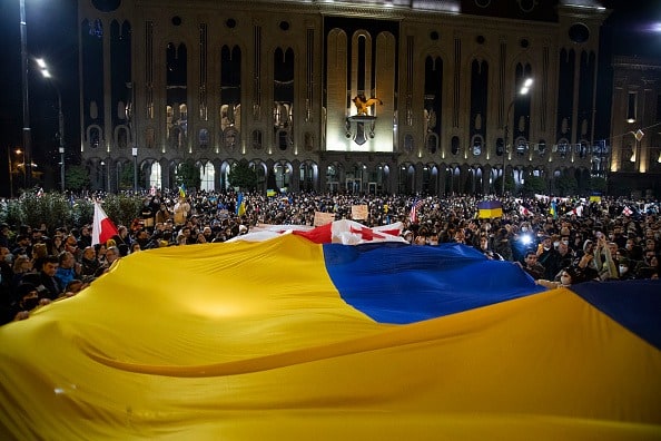 Demonstrators wave a large Ukranian flag on February 24, 2022 in Tbilisi, Georgia as Georgians support Ukraine after Russia began it's military attack to the country. Overnight, Russia began a large-scale attack on Ukraine, with explosions reported in multiple cities and far outside the restive eastern regions held by Russian-backed rebels. (Photo: Getty Images)
