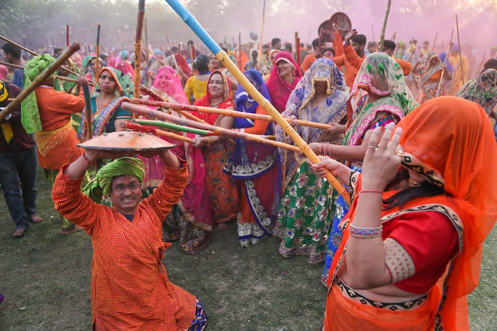 A woman beats a man with sticks as they play Lathmaar Holi at Krishna Janambhoomi Temple, in Mathura, Monday, March 14, 2022. (Source: PTI)
