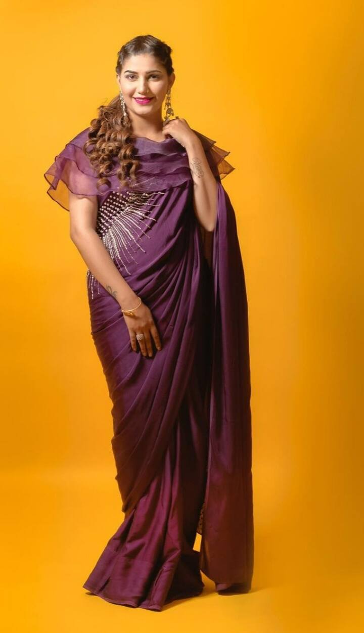 सपना चौधरी ने इस फोटो में डिजाइनर साड़ी कैरी की है. पर्पल रंग की साड़ी के ऊपरी हिस्से में फ्रिल से स्टाइल किया गया है.