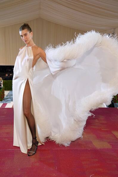 Model Hailey Bieber wore stunning white gown which featured a thigh-high slit. She paired the gown with a feather jacket, sheer black tights, and black heels.