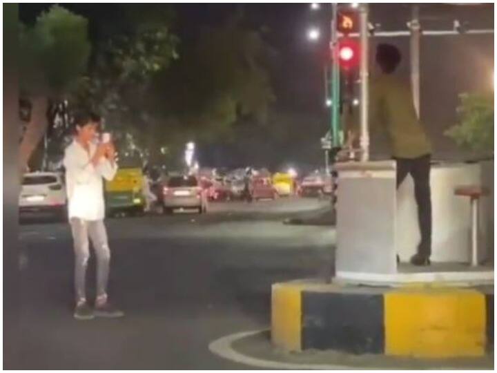 two friends clicking photos at a traffic signal in viral video Watch: ट्रैफिक पुलिस बूथ पर फोटो सेशन करते दिखे दो युवक, वीडियो वायरल 