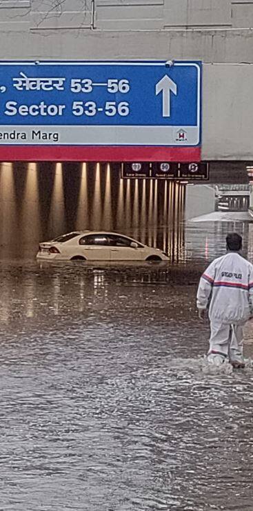 गुरुग्राम के डीएलएफ चरण -1 मेट्रो स्टेशन के पास की ये तस्वीर है. देख सकते हैं कि बारिश की वजह से सड़के पूरी तरह जलमग्न हो गई हैं. गाड़ी भी पानी के अंदर आधी डूब गई है. लोगों को घुटनों-घुटनों पानी से होकर गुजरना पड़ रहा है.