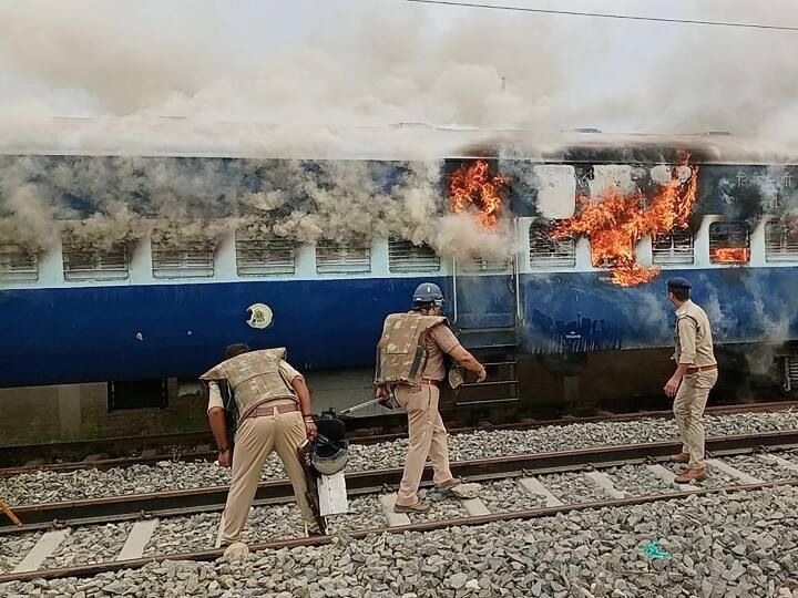 बलिया में प्रदर्शनकारी अभ्यर्थियों के गु्स्से का शिकार हुई एक ट्रेन में लगी आग को बुझाने की कोशिश करते सुरक्षाकर्मी.