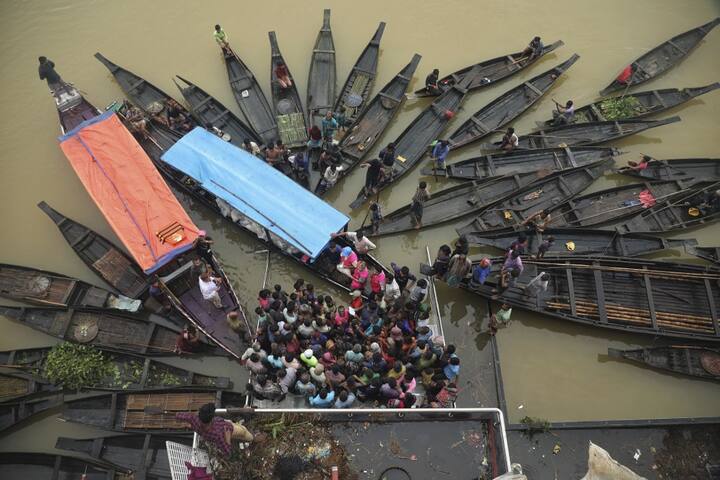 People gather to collect food in a flooded area following heavy monsoon rainfall in Companiganj. (Image Source: AFP)