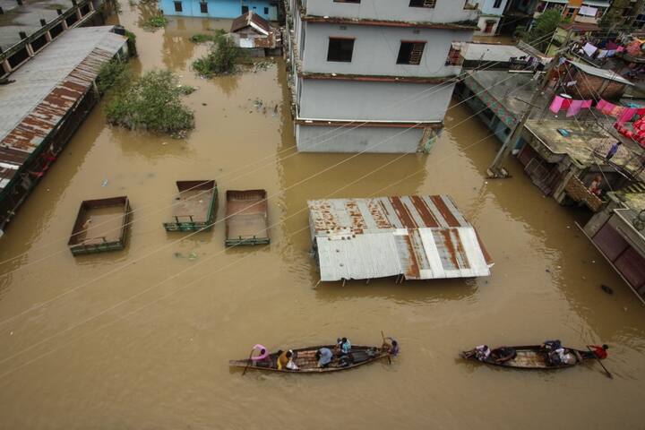 People use boats to wade through a road in a flooded area following heavy monsoon rainfalls in Companiganj. The flooding in Bangladesh has been called by experts as the country's worst since 2004. (Image Source: AFP)